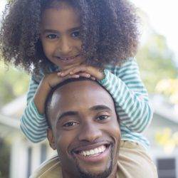 A proud dad with a smiling child on his shoulders to illustrate why people want flexible working