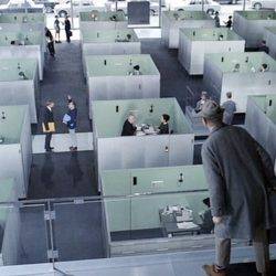 A still from Jacques Tati's film playtime as the protagonist looks out over cubicles in an office