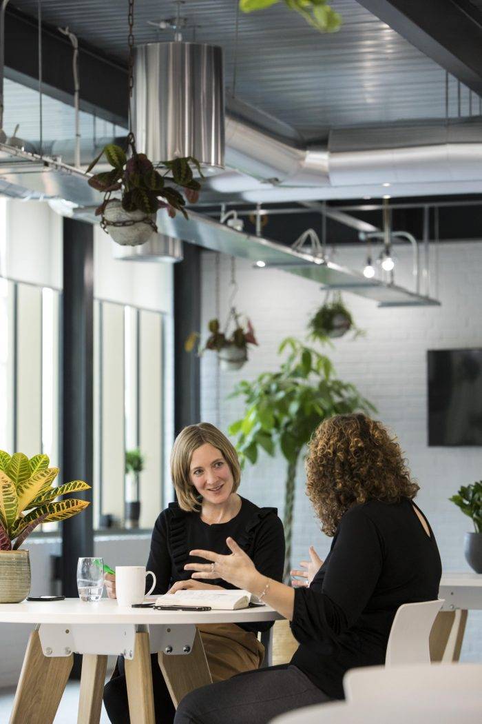 Two women discuss business in an attractive office space