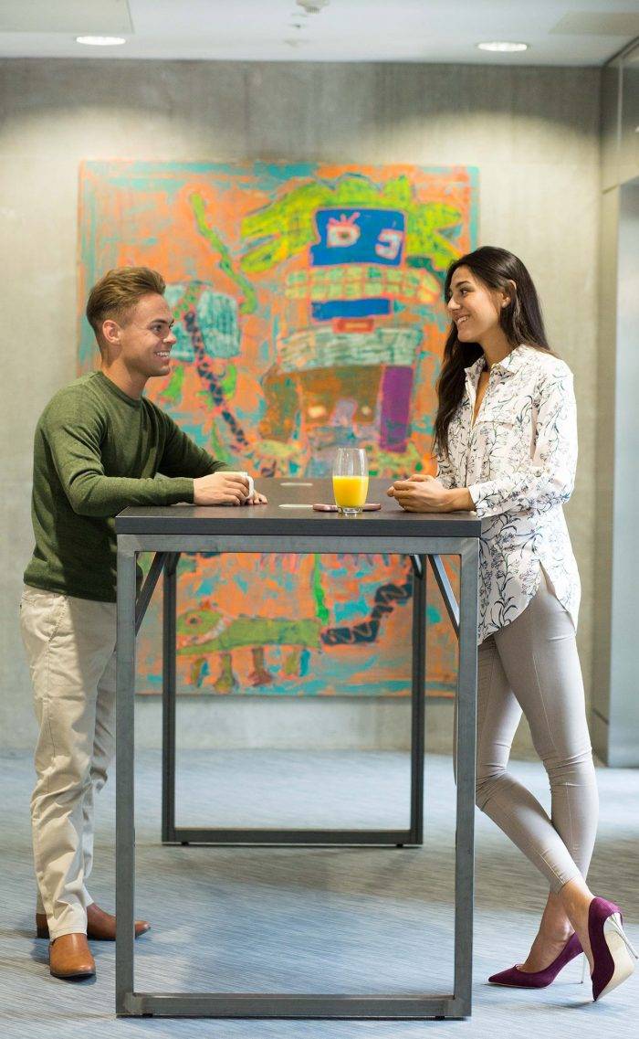 Two colleagues talking at a standing meeting table