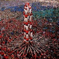 A large and colourful team of people work together to create a human tower