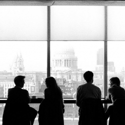 The silhouette of a group of four people in an office window overlooking London