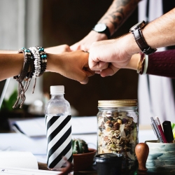 A group of people bump fists to illustrate the challenges facing the HR profession